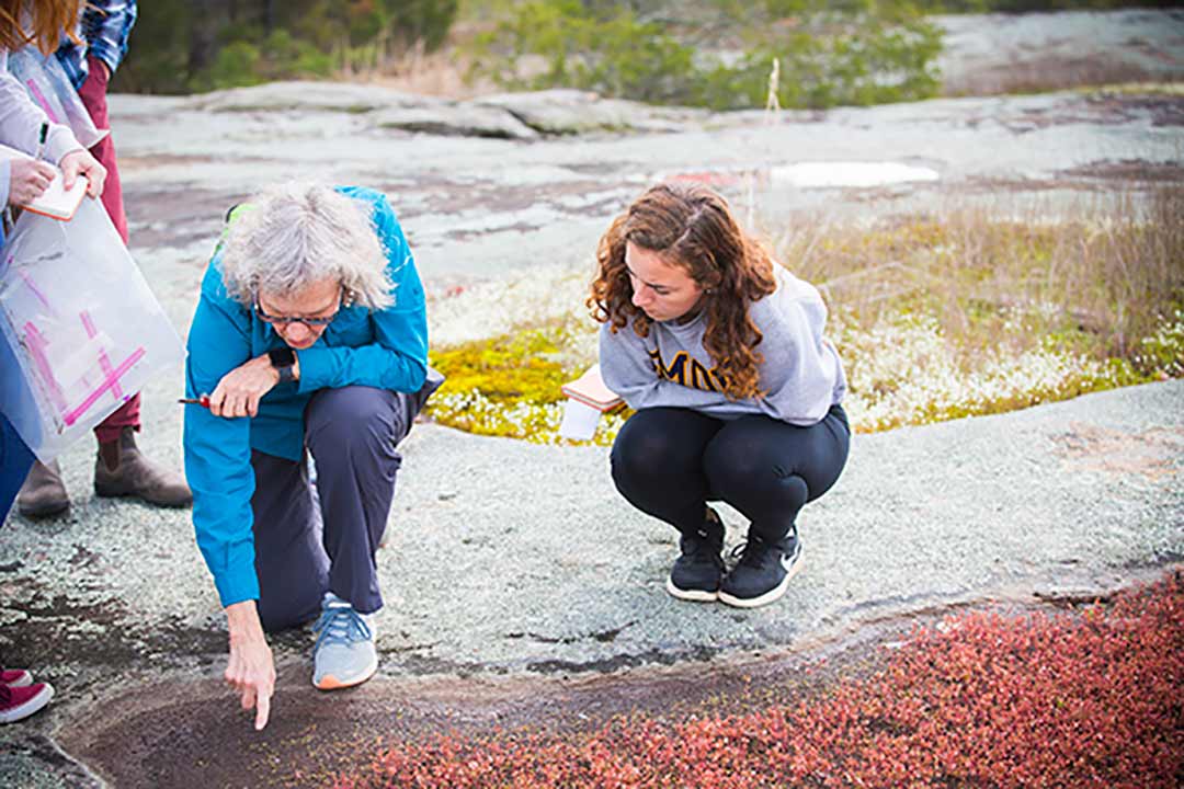 Eloise Carter and a student examine nature samples at a local mountain.