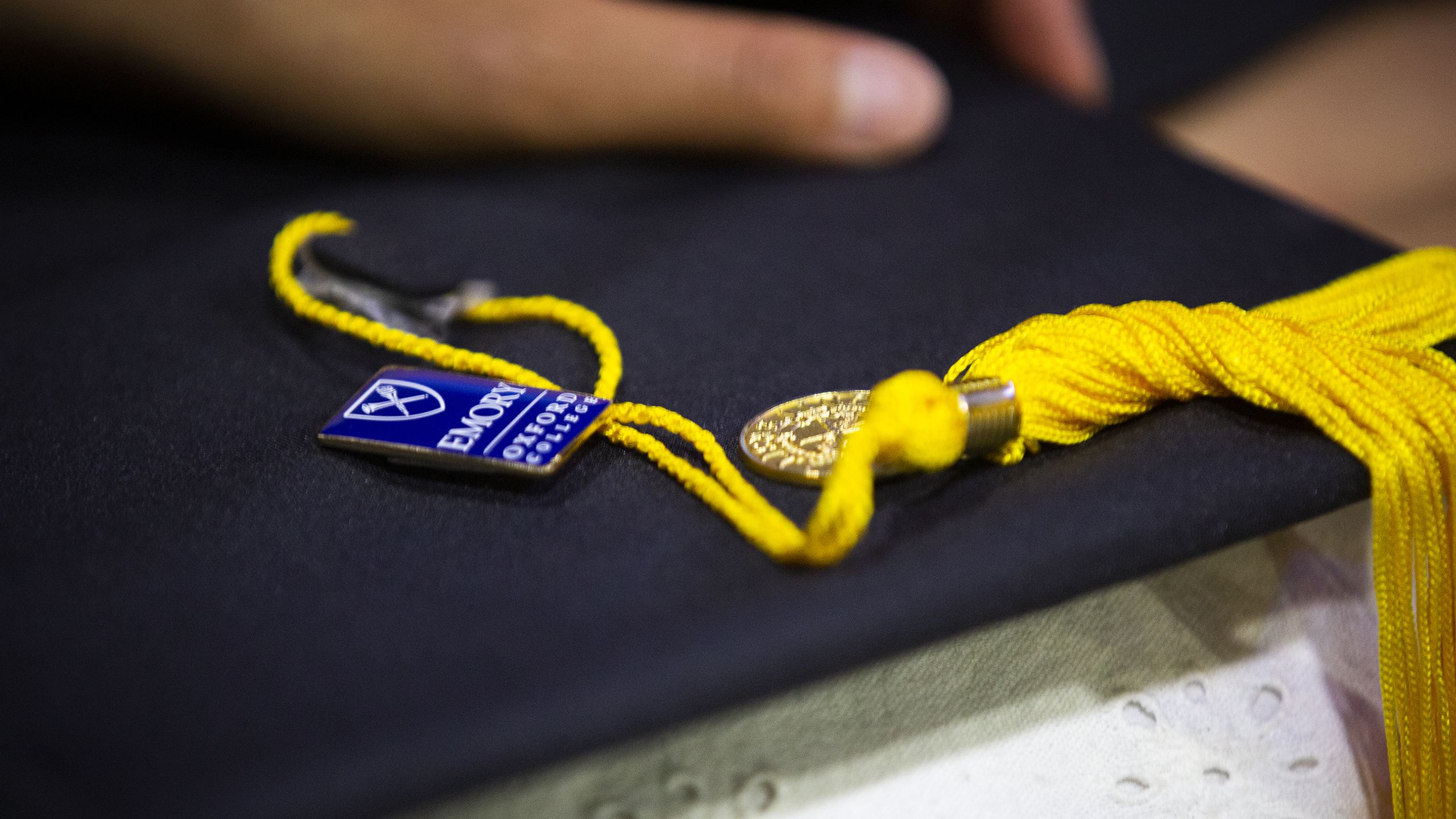 An Oxford College of Emory blue pin sitting on Commencement cap with tassel.h