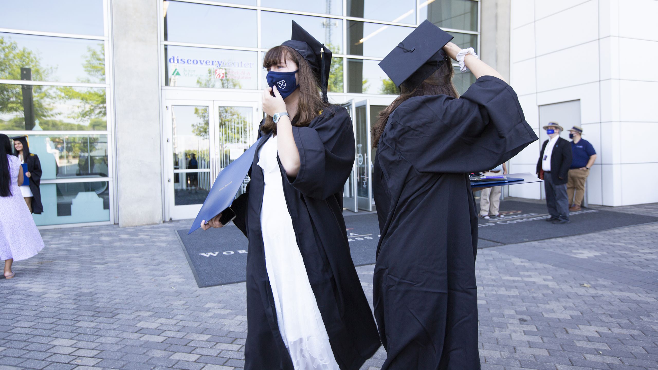 Two graduates stand back to back outside the Georgia World Congress Center.