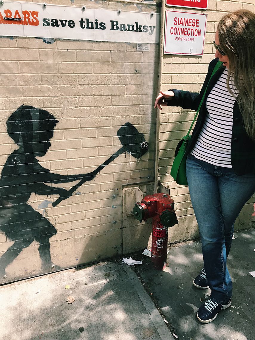Tasha Dobbin-Bennett poses with street art of a boy threatening to smash a real fire hydrant with a mallet..