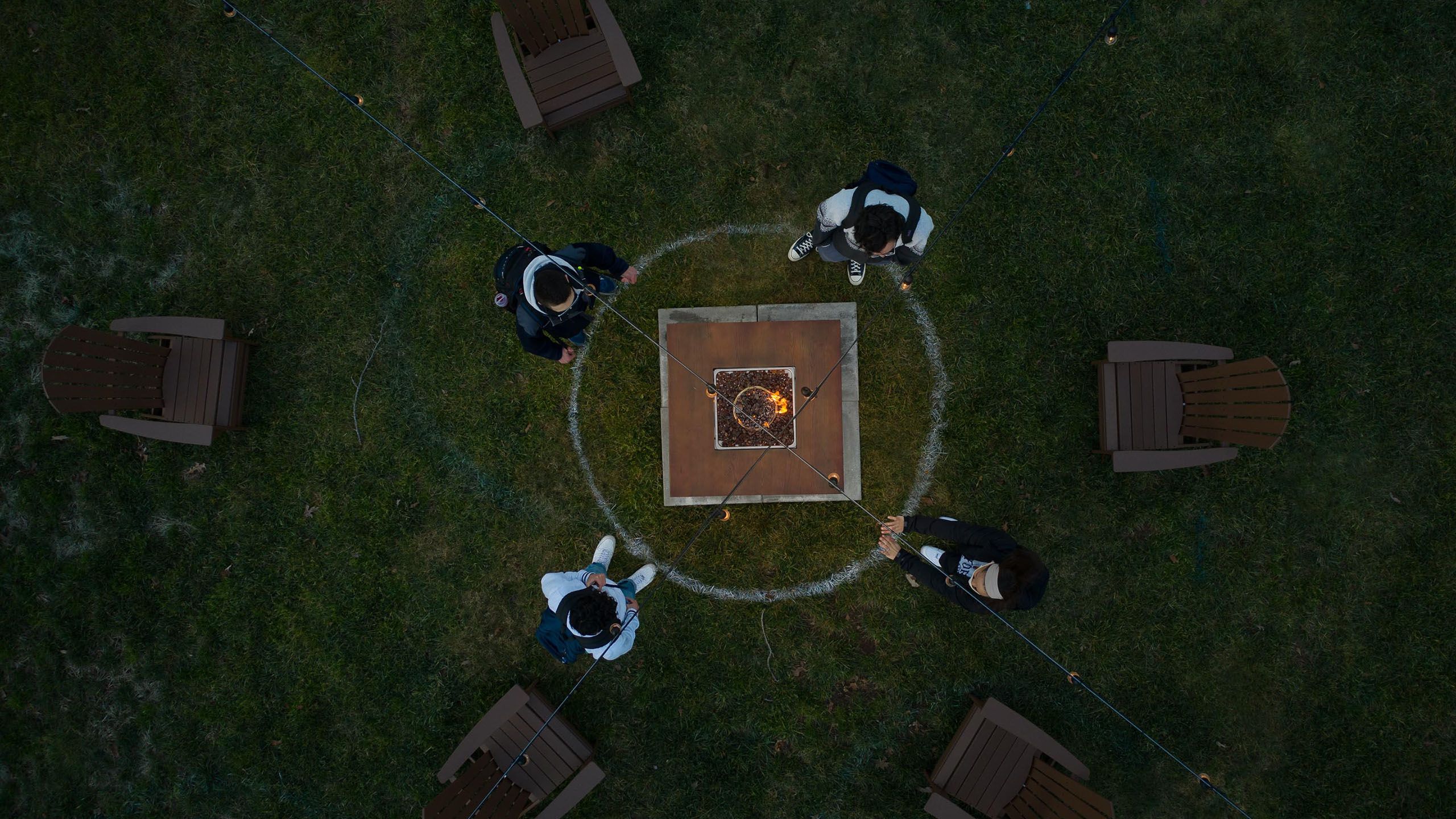 An overhead view of a fire pit surrounded by 4 students.