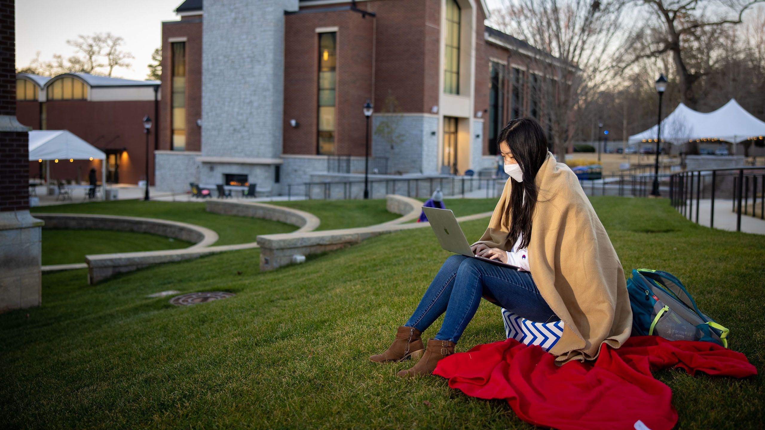 A student on a laptop works in the amphitheater outside the Oxford Science Building.