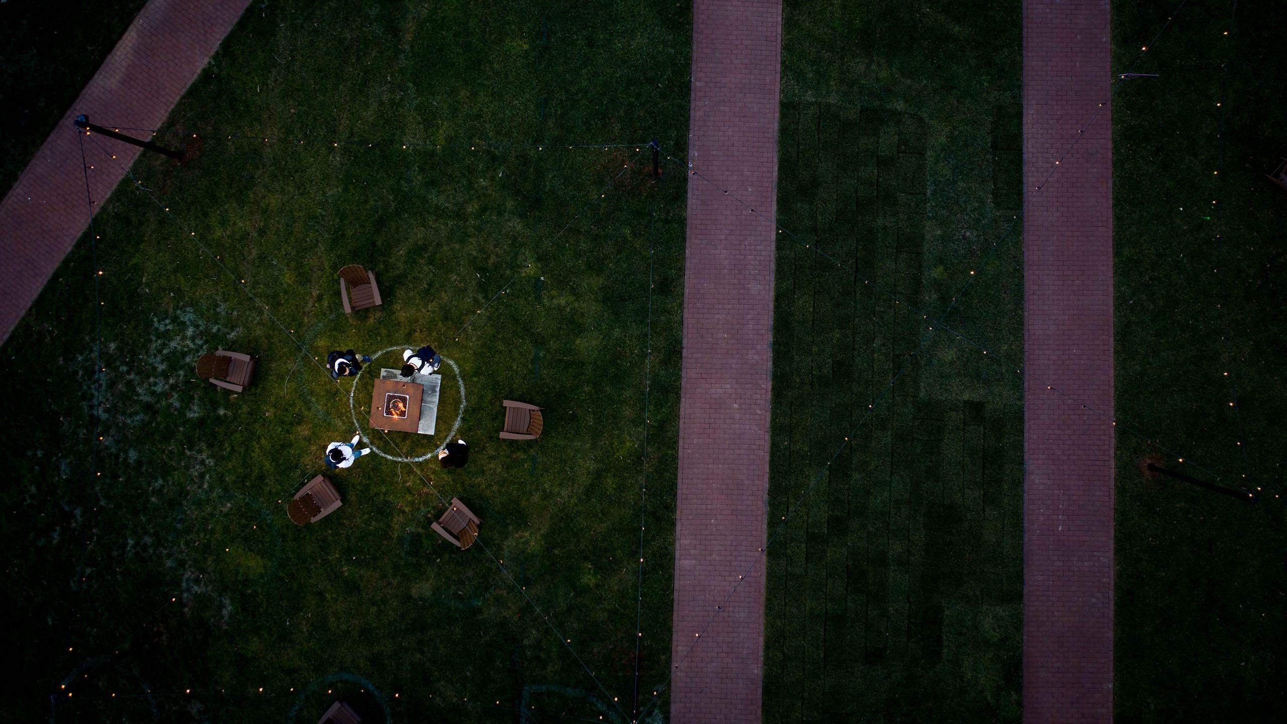An overhead view of a fire pit surrounded by 5 chairs and 4 students.