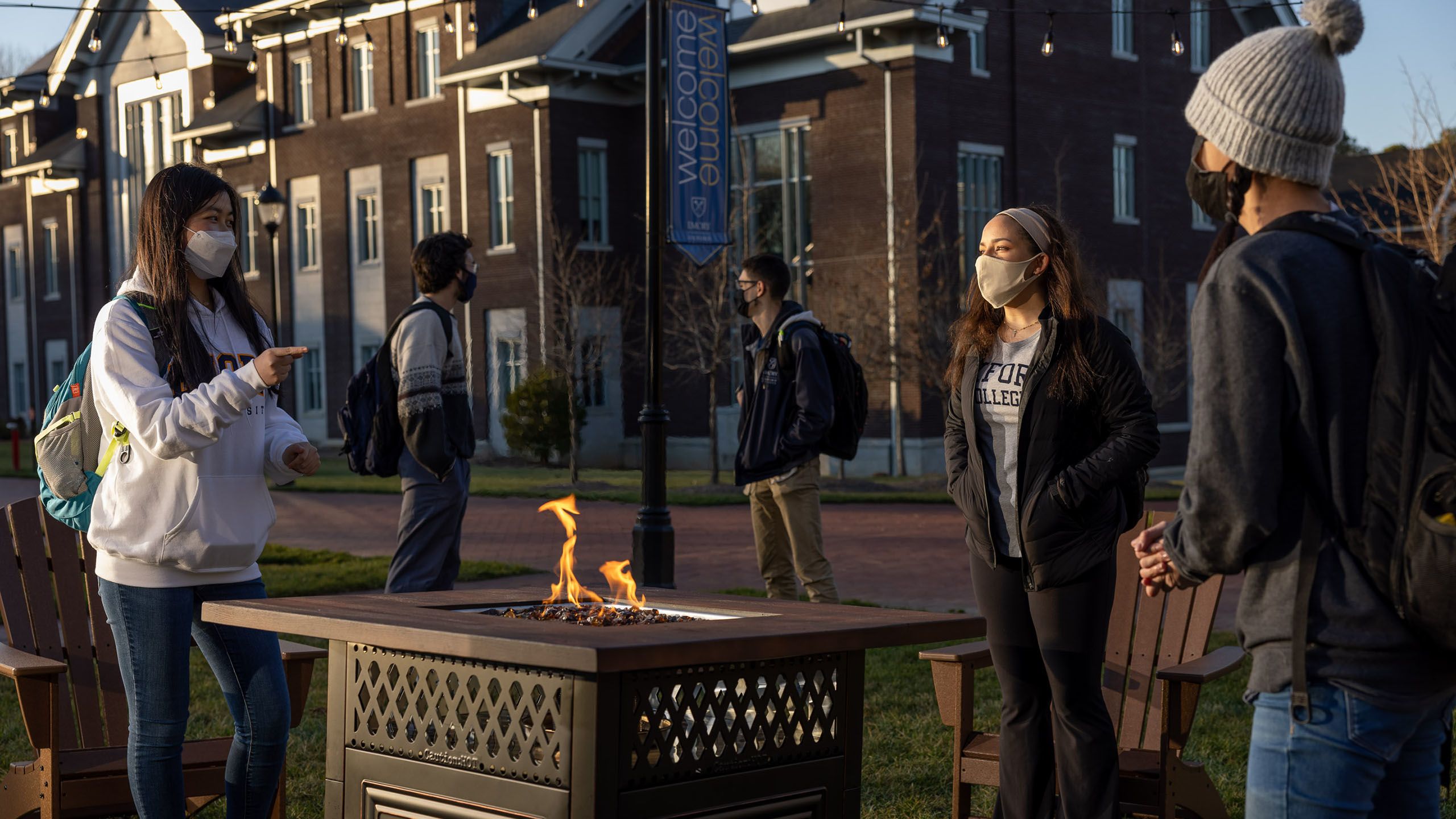 Students wearing masks gather around a fire pit on the Oxford quad.