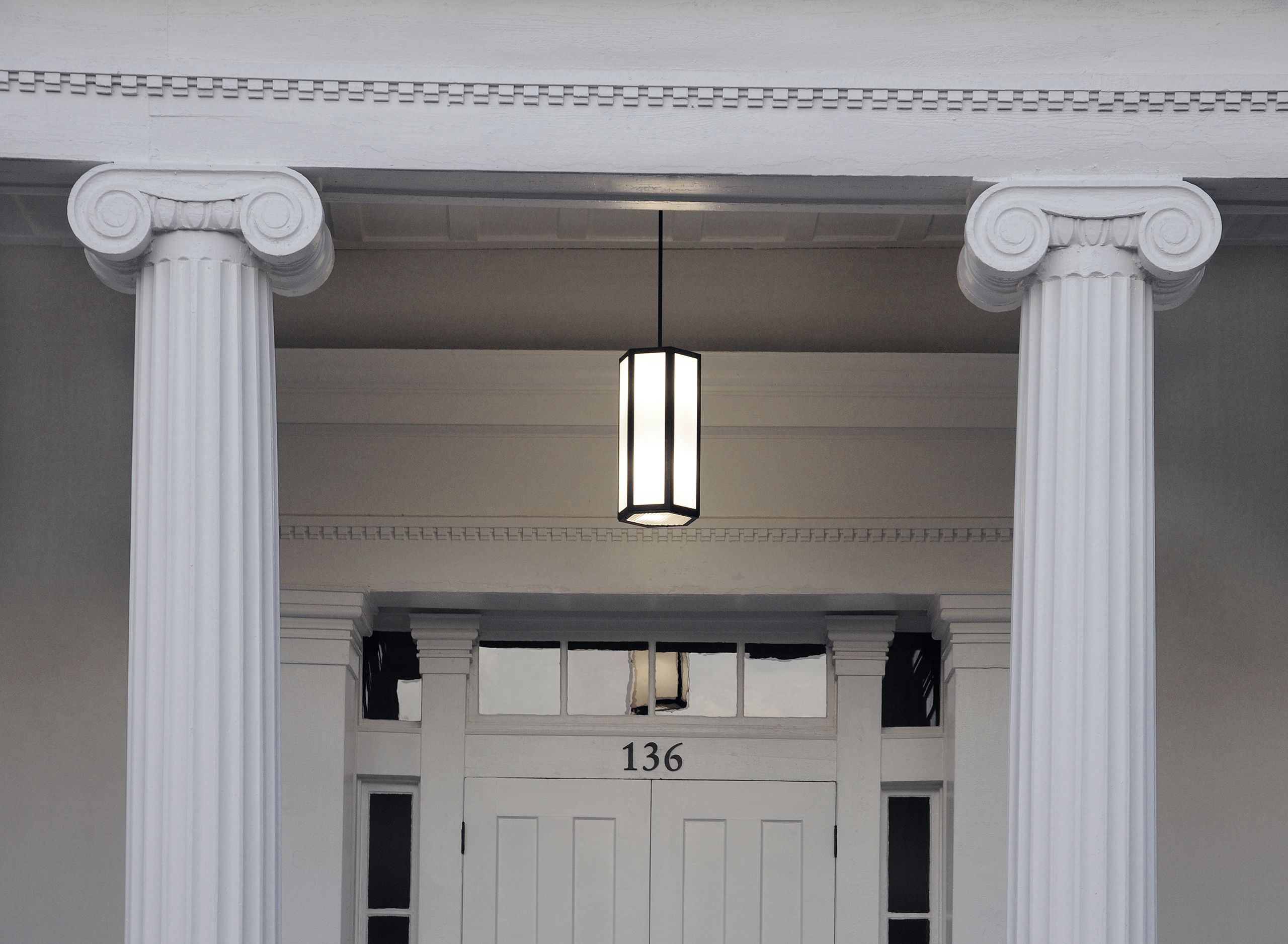 Phi Gamma Hall has a simple, temple-like exterior design, featuring a raised portico with two outer Doric columns and two intermediary Ionic columns. 