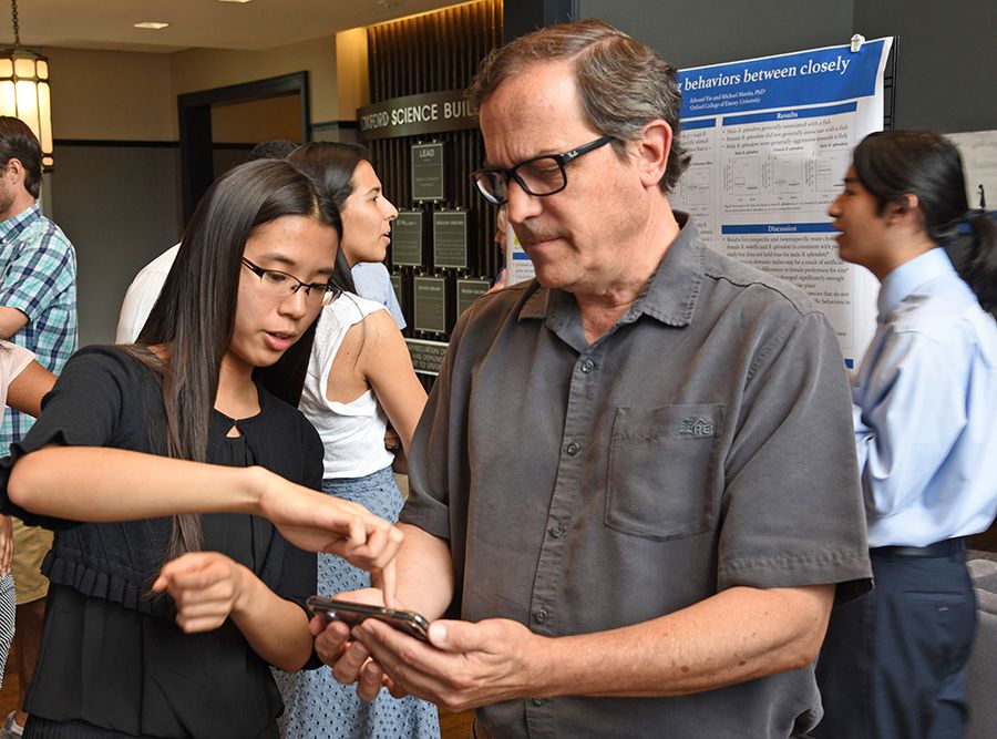 Tiffany Hung shows Dean of Academic Affairs Ken Anderson her research.